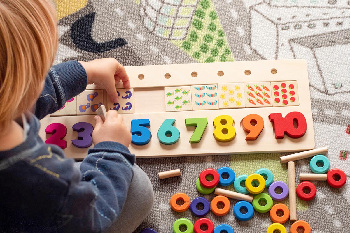 A child happily playing with a colorful wooden number puzzle, focusing on fitting the pieces together.